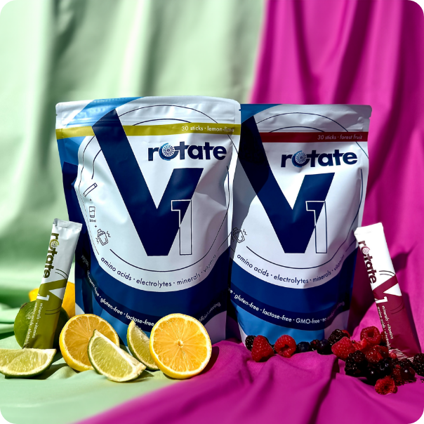 Rotate V1 Doppelpack: Forest Fruit und Lemon Lime Verpackungen nebeneinander mit je einem Stick, umgeben von Zitrusfrüchten und Beeren
