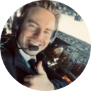 Porträt von Rotate-Gründer Zico als Pilot mit Headset im Flugzeugcockpit, lächelnd mit erhobenem Daumen